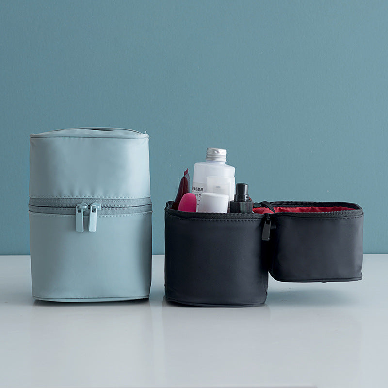 Two cylindrical bags, one light blue and one black, with cosmetic items on a light gray surface against a light blue background.