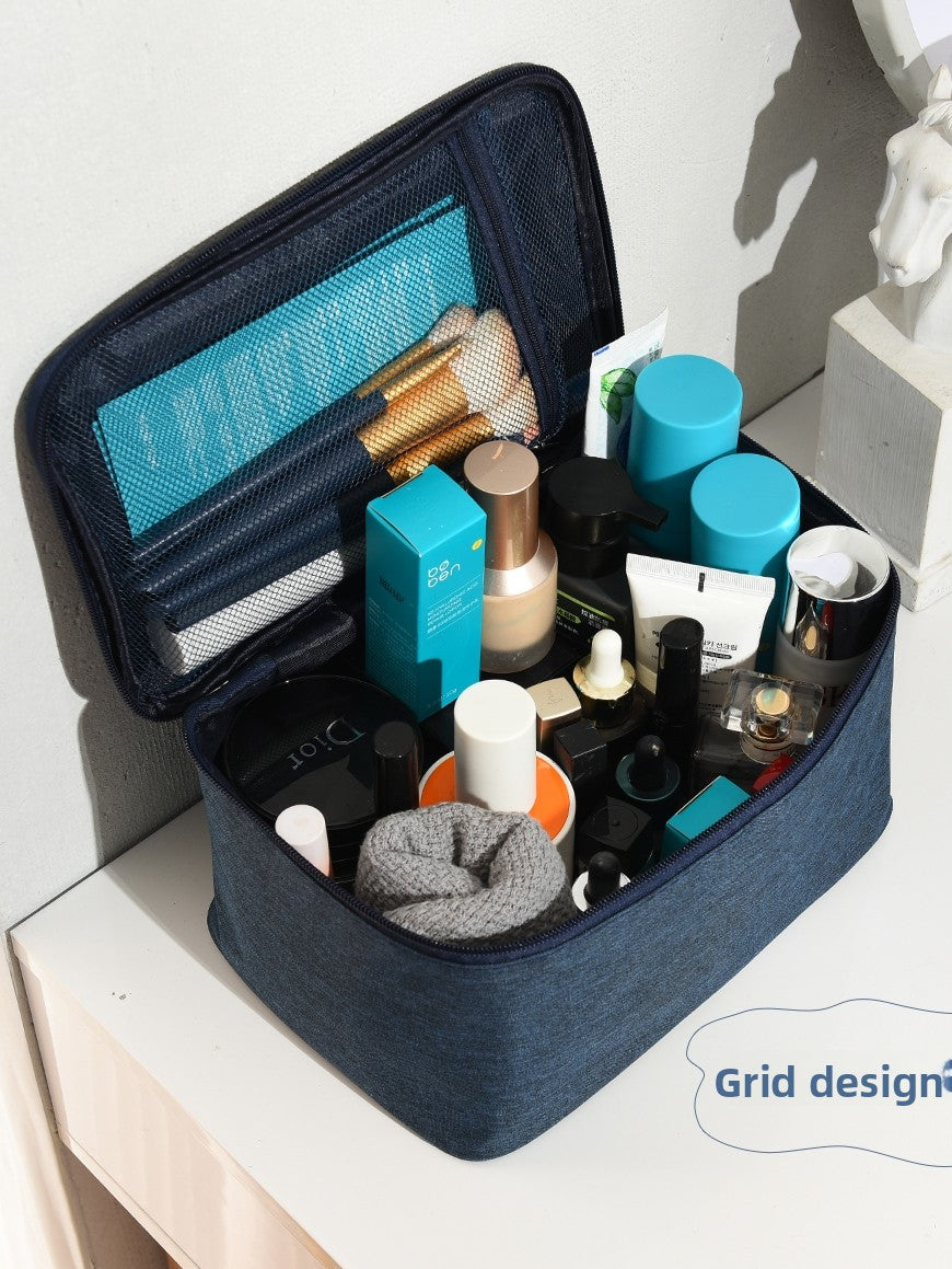 Navy blue cosmetic bag with various travel-sized products on a white surface