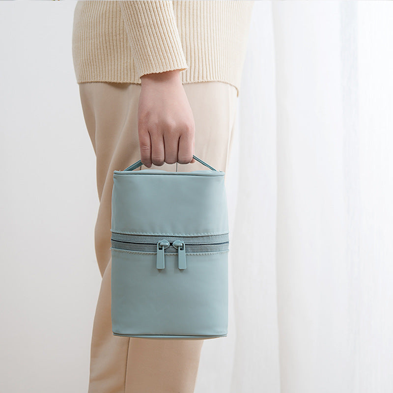 Light blue handbag held by a person wearing beige pants and a cream sweater on a white background