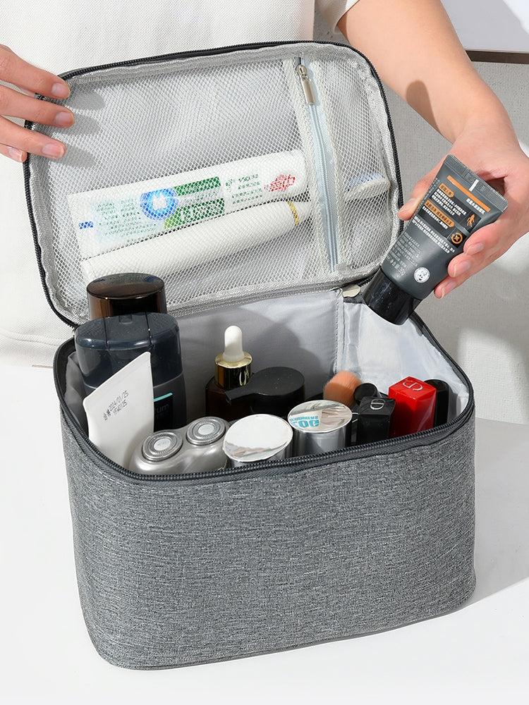 Gray toiletry bag with various travel-sized products on a white background